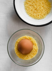 Single egg in a bowl with pasta around