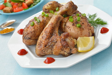 Grilled chicken on a white plate with lemon and ketchup drops