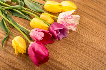 Naklejka na ściany i meble Pink and yellow tulips on wooden table.
