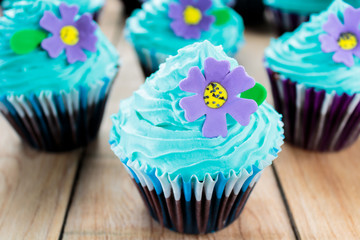 Cupcakes with blue icing and purple flowers