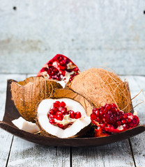 Fresh coconut and red garnet in a wooden bowl,blue background