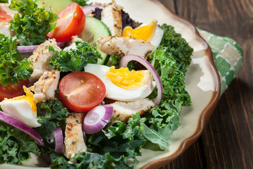 Fresh salad with chicken, tomatoes, eggs and lettuce on plate
