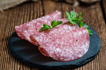 Old wooden table with sliced Salami