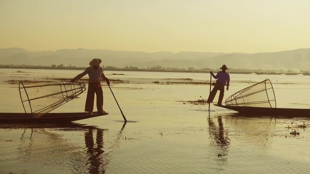 Myanmar travel attraction landmark - Traditional Burmese fishermen with fishing net at Inle lake in Myanmar famous for their distinctive one legged rowing style, 4k
