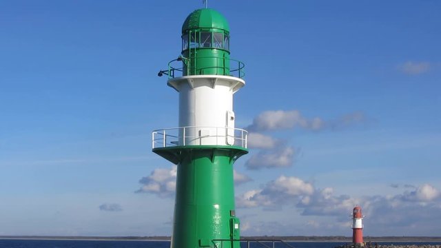 White Ferryboat Approaching a Green White Lighthouse. Blue Sky with some Clouds in the Background.