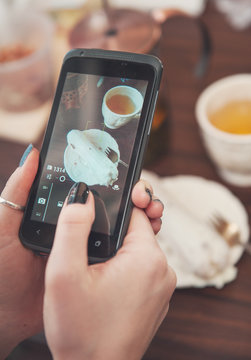 Woman’s hand with smartphone taking food photo for instagram