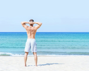 Young, fit man standing on a summer beach