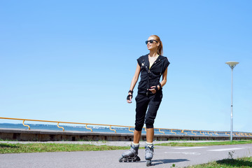 Young, beautiful, sporty and fit girl rollerblading on inline skates.