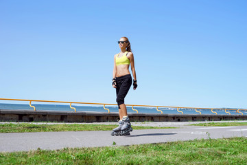 Young, beautiful, sporty and fit girl rollerblading on inline skates.