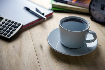 Coffee break concept.Notepad, books, clock and calculator on wooden table.Warm tone with soft selective focus, shallow depth of field.