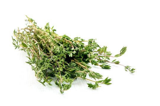 Green thyme herb branches on white wooden table background