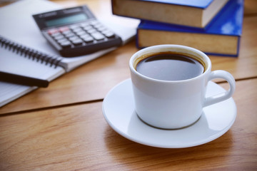 Coffee break. Notepad, books and calculator on wooden table. War