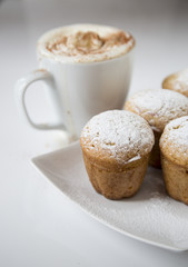 Freshly baked homemade muffins with powdered sugar and coffee