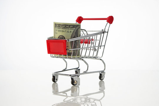Shopping cart filled with one hundred US dollar bilss, against w