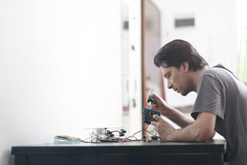 Young man making an electronic device soldering and adjusting the components