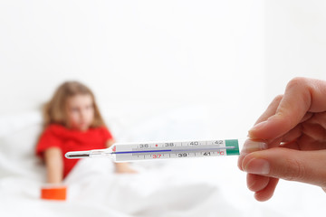 pediatric doctor hand holding a thermometer indicating fever with blury child in background
