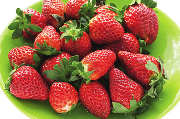 Pile of large red ripe strawberries on green plate