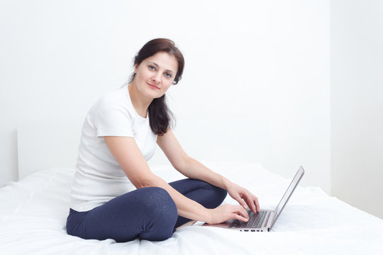 similg happy woman sit in bed with a laptop working from home