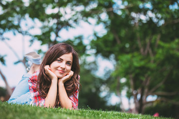 Naklejka na ściany i meble Beautiful Girl lying on green grass.