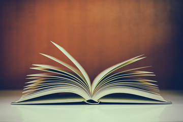 Close up of open book on desk with vintage filter blur background