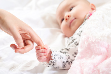 Baby girl grasping her parents finger