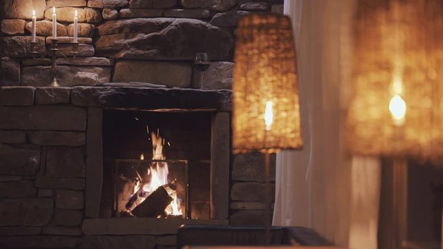Calm fireplace with warm light at night with candle and wine