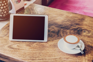 coffee and tablet computer on table with vintage tone.