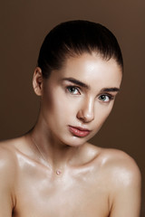 Strobing or Highlighting makeup. Closeup portrait of beautiful girl with strobing highlighter powder. Nice Glow. Perfect retouch. Studio photo beige background. Wet body effect