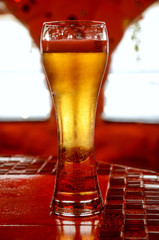Glass of cold beer on a red table
