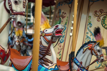 Fototapeta na wymiar Bright carousel in a holiday park. Horses on a traditional fairground vintage carousel. Merry-go-round with horses. (Real Photo)