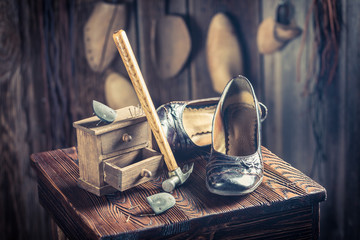 Aged shoemaker workplace with tools, leather and shoes