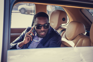 A black man talking by smartphone in the car.