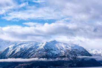 Fototapeta na wymiar Snow caped mountain range under a blue cloudy sky