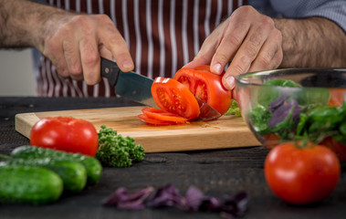 Male hands cutting vegetables for salad