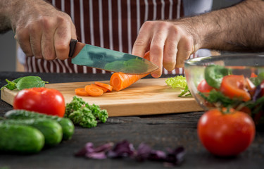 Male hands cutting vegetables for salad