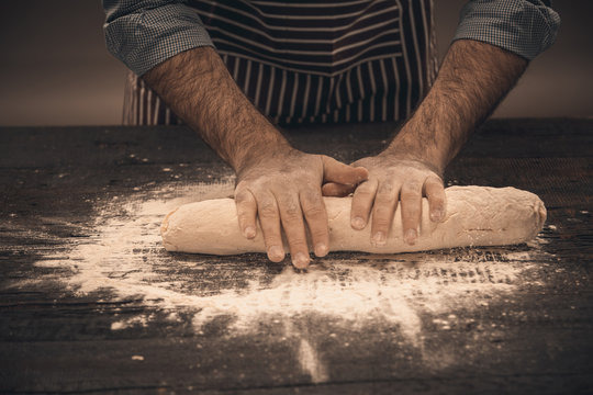 Male hands knead the dough.