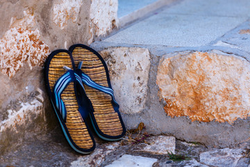 Beach flip-flops on the old wall background