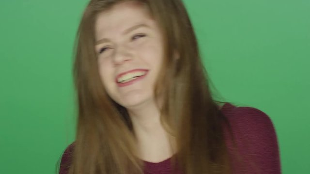 Young brunette woman laughing and smiling, on a green screen studio background 
