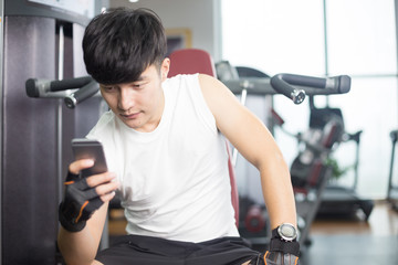 Fototapeta na wymiar young handsome asian man using smart phone in modern gym