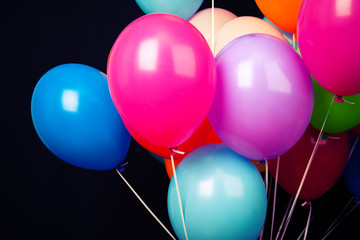 Group of colorful balloons on ribbons on black