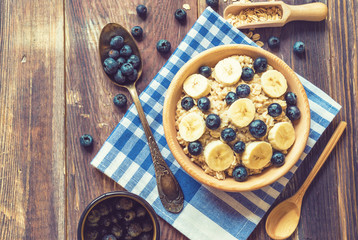 Oatmeal with blueberries and banana in wooden bowl