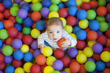 Fototapeta na wymiar baby boy playing in the playground balls pool