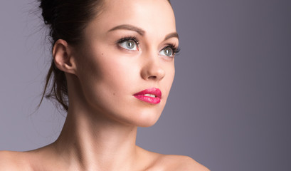 Fototapeta premium Closeup portrait of a beautiful young woman on a gray background