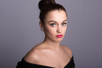 Portrait of a beautiful young woman on a gray background. Bare s