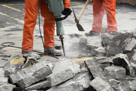 workers at construction site demolishing asphalt