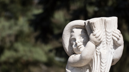 A white sculpture/statue of a child holding a horn