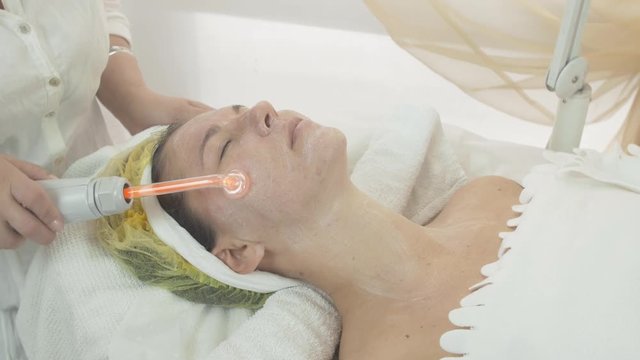 Close up of cosmetologist use darsonval on woman face in beauty saloon. Skincare. Cosmetic procedure.