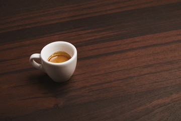 Side view of perfect espresso in small white ceramic cup on red wooden table in cafe shop, isolated on side