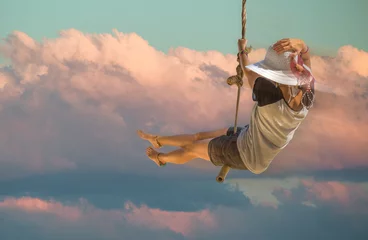 Junge Frau mit Shorts, Hemd und Hut mit breiter Krempe, die mit Sonnenuntergang und Wolkenhintergrund schwingt. Freiheitskonzept. © bennymarty