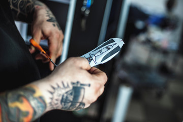 Obraz premium Male tattoo artist shows a sketch of the future tattoo client